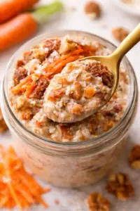 Top view of a spoonful of carrot cake cottage cheese overnight oats with shredded carrots, raisins, walnuts, and creamy oat mixture