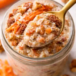 carrot cake cottage cheese- Carrot Cake Cottage Cheese Overnight Oats Top view of a spoonful of carrot cake cottage cheese overnight oats with shredded carrots, raisins, walnuts, and creamy oat mixture