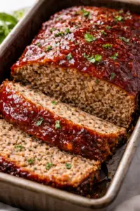 Juicy homemade meatloaf sliced in loaf pan with glossy ketchup brown sugar glaze and tender interior
