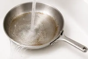 rinsing stainless steel pan after cleaning paste to remove residue and buildup