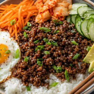 korean ground beef bowl- Korean Ground Beef Bowl Korean beef bowl with sticky ground beef over white rice topped with kimchi, cucumber, avocado, sesame seeds, green onions, and a fried egg.
