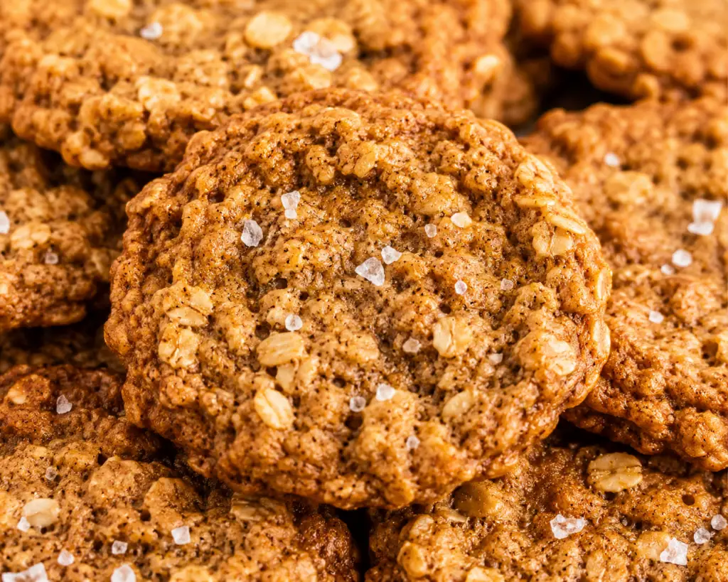 Bakery-style brown butter oatmeal cookies with warm spices and flaky sea salt stacked together, featuring chewy centers, crisp edges, and old-fashioned rolled oats.