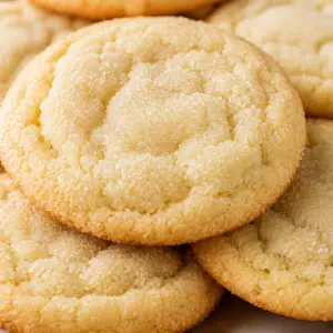 sugar cookies- Chewy Sugar Cookies Close-up of soft and chewy sugar cookies with lightly golden edges and tender centers, stacked on a plate and coated in sparkling sugar.