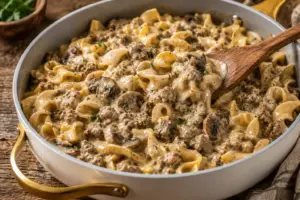 Creamy ground beef stroganoff served in a white Caraway sauté pan with gold handles, featuring egg noodles, mushrooms, and rich beef sauce.