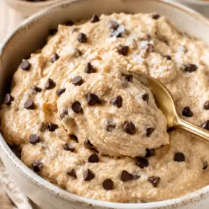 Rustic bowl of creamy homemade cottage cheese cookie dough topped with mini chocolate chips and flaky sea salt on a farmhouse wooden table.