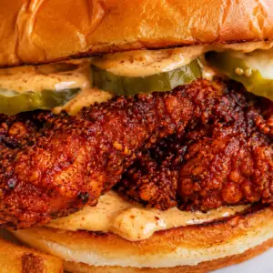 dave's hot chicken- Dave's Hot Chicken Recipe (Copycat) Close-up of a homemade Dave's Hot Chicken sandwich with crispy Nashville-style fried chicken, creamy Dave's sauce, dill pickle slices, and a toasted brioche bun served with crispy French fries.