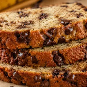 eggless banana bread- Eggless Banana Bread Stacked slices of moist eggless banana bread with chocolate chips showing a soft, fluffy crumb and golden crust.