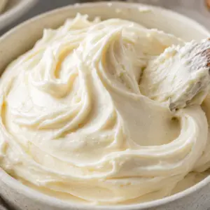 homemade frosting- Homemade Frosting Close-up of creamy homemade vanilla frosting swirled in a ceramic bowl with a wooden spatula.